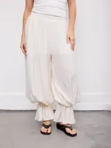 Pantalón negro de corte amplio, con cintura elástica fruncida y diseño abombacho con volados en los tobillos.
