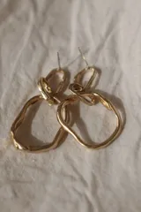 Aros colgantes de diseño artesanal con eslabones irregulares de textura orgánica y acabado en tono dorado.