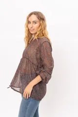 Blusa de gasa con estampado paisley en tonos marrones y azules, de corte holgado con ajuste en la cintura mediante cordones laterales y mangas tres cuartos con puños elásticos.