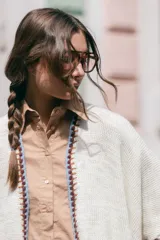 Poncho liviano de tejido de punto color blanco, con bordes decorados en crochet multicolor y flecos en el ruedo.