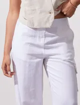Pantalón de lino color blanco, de corte recto y tiro alto. Presenta bolsillos laterales tipo cargo y pretina elastizada en la parte trasera.