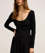 Vestido midi negro con parte superior de rib acanalado, escote en U y mangas largas. La falda es de tricolina lisa.