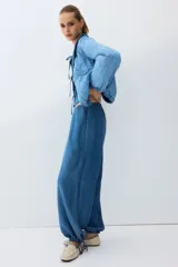 Pantalón de denim liviano, color azul, con cintura elástica y cordones ajustables en los tobillos.