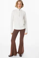 Sweater de punto gris con textura de ochos, cuello alto con cierre frontal parcial, manga larga y puños y ruedo acanalados.