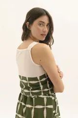 Top de tirantes anchos con diseño bicolor, presentando una parte superior en color crudo y una parte inferior estampada con un patrón geométrico de cuadrícula en negro y blanco.