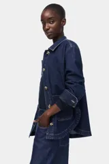 Campera camisera de denim azul oscuro con cuello, cierre frontal de botones, hombros caídos, mangas largas con puños abotonados y dos bolsillos delanteros de parche.