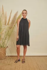 Vestido corto negro con escote halter adornado con perlas, diseño holgado y detalles de perlas en la parte inferior de la falda.