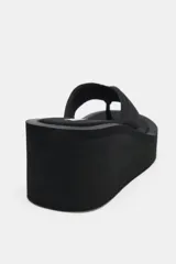 Sandalia tipo ojota con plataforma alta, confeccionada en tejido negro con tiras acolchadas y suela de goma.