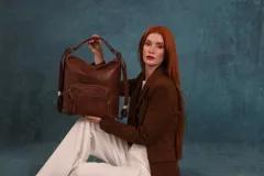 Mochila cartera de símil cuero color marrón, con compartimento principal amplio y bolsillos frontales con cierre. Cuenta con correas ajustables y asa superior para llevar al hombro o como mochila.