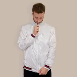 Campera bomber blanca de nylon con cierre frontal, cuello alto y puños y ruedo acanalados con detalles en gris, rojo y negro.