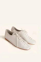Zapato tipo oxford plano de cuero vacuno en color azul marino, con cordones al tono y suela de cuero.