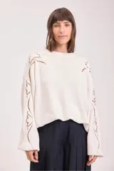 Sweater de punto color negro, de corte holgado y manga larga, con detalle de bordado calado en los hombros y a lo largo de las mangas.