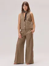 Chaleco negro sin mangas, de corte recto y largo a la cintura, con cuello redondo y cierre frontal oculto.