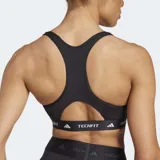 Top deportivo negro de ajuste ceñido, con escote redondo y tirantes anchos. Presenta una banda elástica bajo el busto con la inscripción 'TECHFIT' y el logo de Adidas en blanco en el frente.