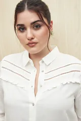 Camisa verde clara de manga larga confeccionada en viscosa ligera, con cuello clásico, cierre frontal con botones, detalles calados en la parte superior y pequeños volados.