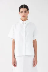 Camisa clásica blanca de manga corta, con cuello camisero y cierre frontal de botones.
