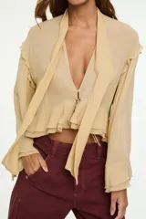 Blusa color tostado con escote en V profundo, volados en la parte inferior y en las mangas largas amplias, y un lazo frontal ajustable.