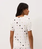Blusa de pijama de color blanco con estampado de corazones en tonos marrones y beige, cuello redondo y mangas cortas.