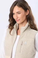 Chaleco de sherpa combinado en tonos beige, con cuello alto y cierre frontal. Presenta una textura suave y abrigada, ideal para capas adicionales.