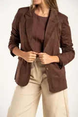 Blazer negro de textura gamuzada con solapas clásicas, cierre frontal de dos botones y bolsillos laterales con solapa.