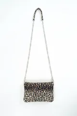 Cartera bandolera pequeña con estampado animal print tipo leopardo, solapa frontal y correa combinada de eslabones metálicos plateados y sección superior en el mismo estampado.
