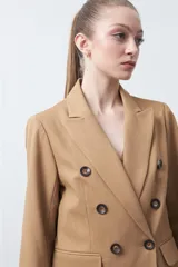 Blazer sastrero negro de doble botonadura con botones marrones, cuello solapa y mangas tres cuartos. Tiene dos bolsillos delanteros con solapa.