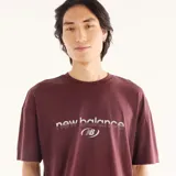 Remera de algodón New Balance color bordó, de manga corta y cuello redondo acanalado, con estampado gráfico en relieve con el nombre de la marca en el centro del pecho y diseño de silueta cuadrada.
