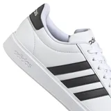 Championes adidas Grand Court 2.0 de estilo urbano, color blanco con las icónicas tres tiras laterales en color negro y detalle en el talón. Presentan suela de goma plana y cierre con cordones.
