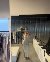 Vestido largo de tejido de punto blanco marfil, con escote halter anudado y aberturas pronunciadas en los laterales de la cintura. Presenta un tajo en la falda.