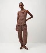 Pantalón modelo aladino de corte holgado y fluido, confeccionado en chiffon con estampado de cuadros. Presenta cintura elástica y puños ajustados en el dobladillo, ofreciendo una silueta tipo globo.