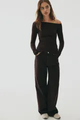 Remera de manga larga color marrón oscuro, con escote asimétrico que deja un hombro al descubierto. Presenta frunces laterales que generan un efecto drapeado en el torso.