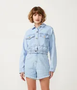 Campera cropped de jean celeste con escote solapa, manga larga, bolsillos delanteros y elástico en el bajo.