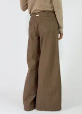 Pantalón de corte ancho y tiro medio, confeccionado en tela de textura rústica color marrón. Presenta cintura elástica con cordón de ajuste frontal, bolsillos laterales y costuras reforzadas en el ruedo.