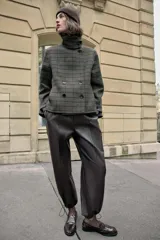 Pantalón de tiro alto confeccionado en material con efecto piel, con cintura elástica, bolsillos delanteros y nervio marcado en el frente. Presenta un diseño bombacho con bajo ajustable mediante cordones elásticos.