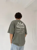 Remera oversize gris con efecto acid wash y estampa frontal con la leyenda "WORLDWIDE TOUR" en tipografía gótica.