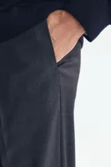 Pantalón de traje negro, de corte regular fit y silueta clásica, con bolsillos laterales y traseros ribeteados, cierre con cremallera y botón oculto.