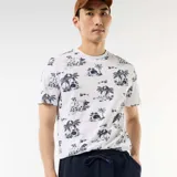 Remera blanca con estampado tropical de palmeras y paisajes en azul oscuro, de manga corta y cuello redondo.