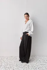 Pantalón wide leg de tiro medio y calce amplio, color marrón, con pinzas delanteras, cierre frontal y bolsillos laterales funcionales.