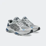 Championes Asics modelo Gel NYC 2.0, con diseño inspirado en el running de alto rendimiento. Presenta una combinación de malla y superposiciones de gamuza en tonos grises, con detalles en azul vibrante. Incorpora tecnología GEL y amortiguación FF BLAST PLUS en la mediasuela para mayor confort.