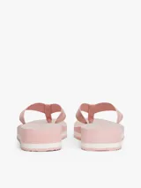 Ojotas de mujer con plataforma tipo cuña, base rosa con rayas verticales grises y entresuela blanca con borde dentado. Las tiras son de textil trenzado rosa con detalles brillantes.