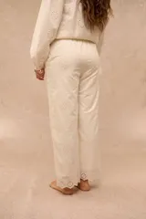 Pantalón Anel de corte recto y holgado, color blanco, confeccionado en tela con diseño bordado o broderie con motivos florales y detalles calados en toda la prenda, incluyendo los bolsillos laterales y el ruedo.
