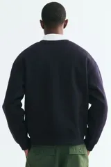 Buzo de cuello redondo color negro, con diseño liso, hombros caídos y puños y dobladillo acanalados.