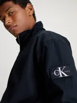 Campera negra con cierre frontal, cuello alto, puños y cintura elastizados. Presenta el logo de Calvin Klein Jeans en el brazo izquierdo. Corte relaxed.