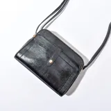 Bandolera negra de cuero sintético con correa larga regulable.