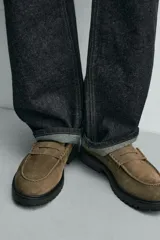 Mocasín de vestir para hombre, confeccionado en piel con acabado de serraje en color marrón oscuro. Presenta un diseño clásico con detalle de antifaz en el empeine, horma redonda y una suela track robusta de goma.
