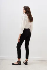 Pantalon negro de corte ajustado, confeccionado en una combinación de materiales que incluye paneles de efecto cuero en la parte frontal y laterales, con diseño de costuras horizontales en las rodillas.