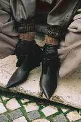 Guantes cortos de efecto piel en color negro, con costuras decorativas en el dorso y puño de tejido de punto trenzado en mezcla de lana color marrón.
