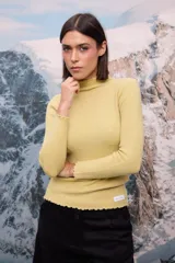 Polera de tejido de punto fino color blanco, con cuello alto, mangas largas y terminaciones con detalle de ondas en puños, cuello y ruedo.