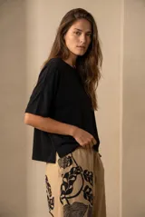 Remera negra de corte oversize, con cuello redondo y mangas cortas de caída fluida. Presenta un diseño minimalista con aberturas laterales en el ruedo.