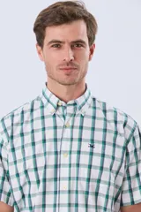 Camisa de manga corta a cuadros en tonos blanco, azul y gris, con cuello abotonado, bolsillo en el pecho y cierre frontal con botones.